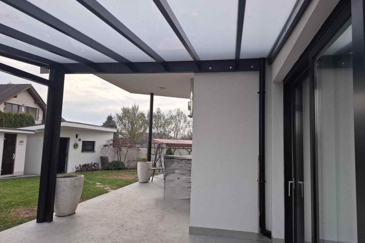 Pergola na terasu s čiernou hliníkovou konštrukciou a polykarbonátovou strechou napojená na rodinný dom, hormax